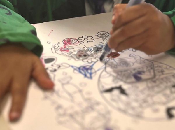 Close up of a child colouring a creative drawing with markers during an arts and crafts activity.